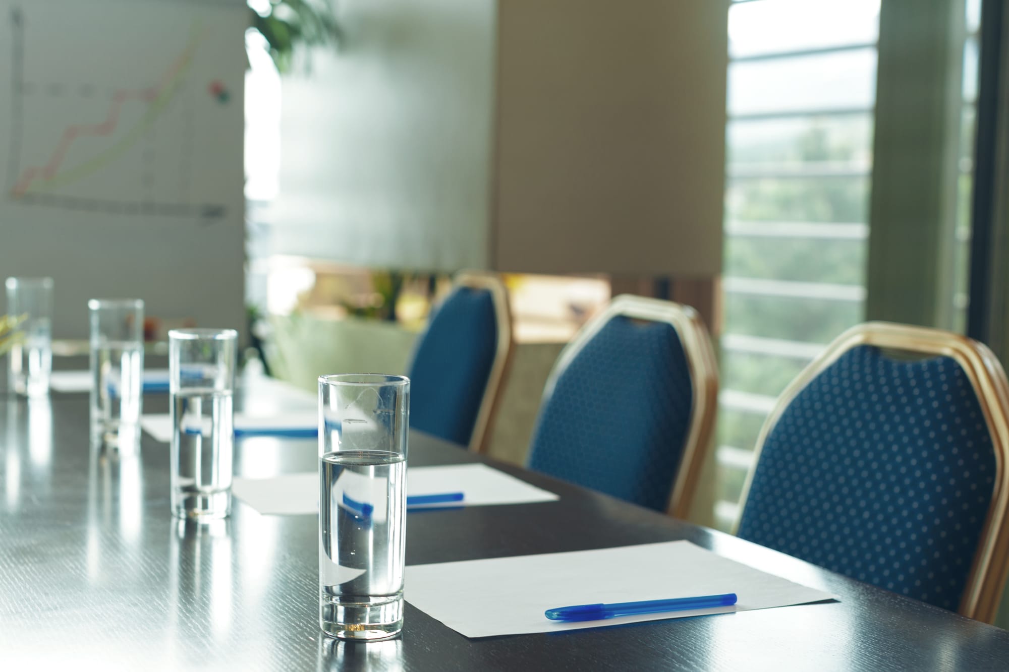 Meeting room with water, notepad and pens on table