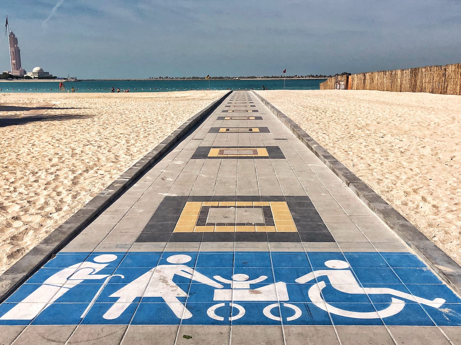pathway on beach on sand with signs of elderly person, woman with pram and wheelchair.