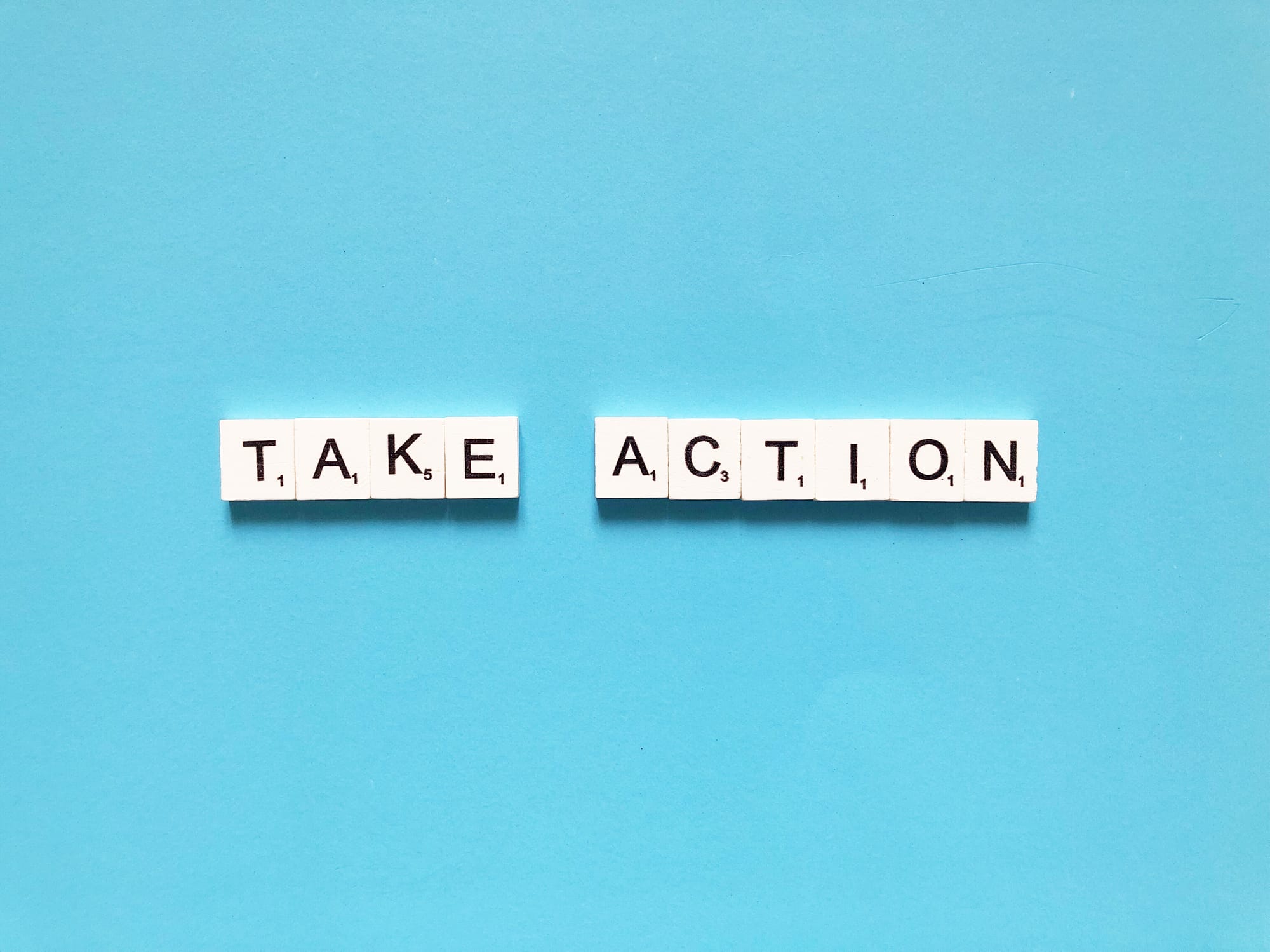 take action scrabble letters on blue blackground